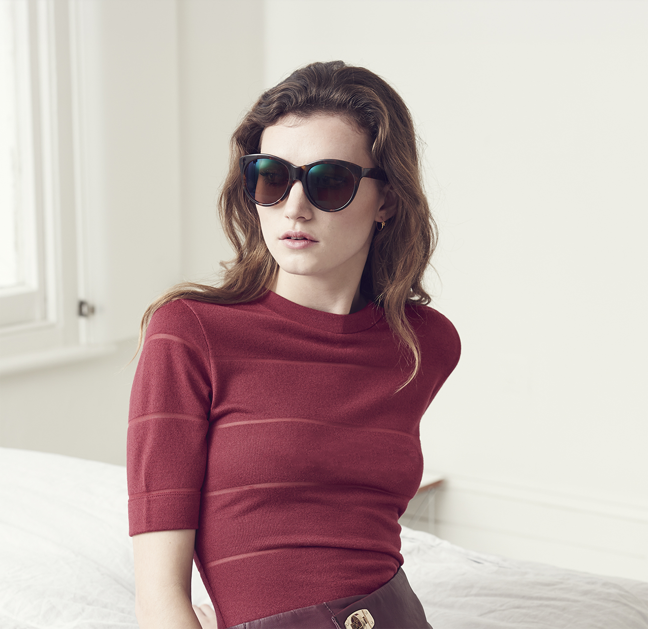 Model wearing Elenore's high-angled sunglasses with a burgundy top